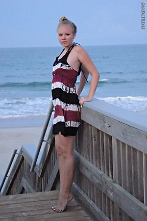 tall teen female model with hair in a bun wearing a sundress at the beach at sunset