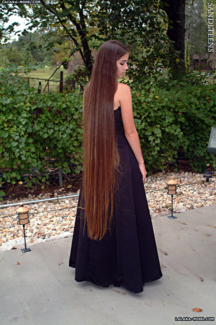 teen female model wearing a long gown showing her long, brown hair down her back