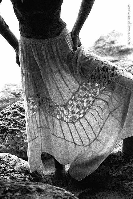 beautiful blonde teen female model wearing a thin, lace top and long beach skirt barefoot